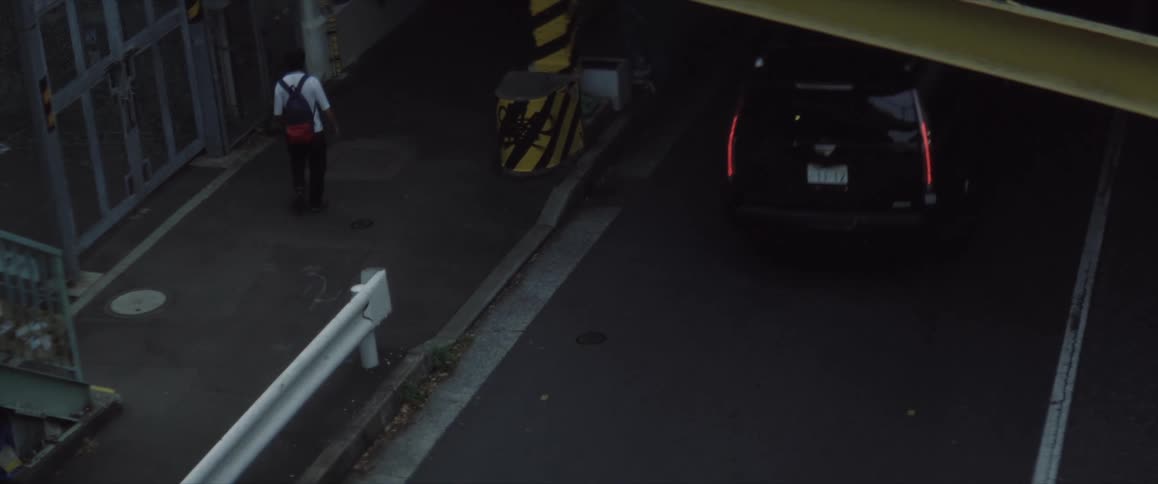Cars and motorcycles drive on the road in Japan as a pedestrian walks by
