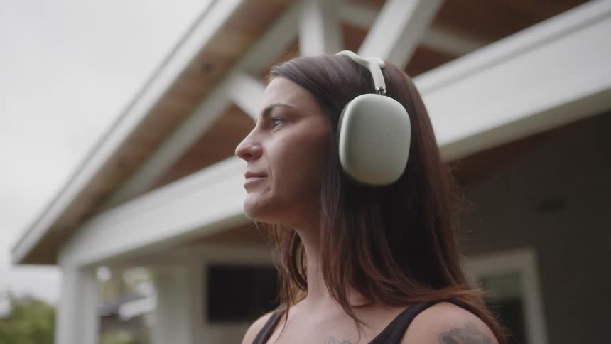A woman with brown hair tattoos and a black top wears headphones