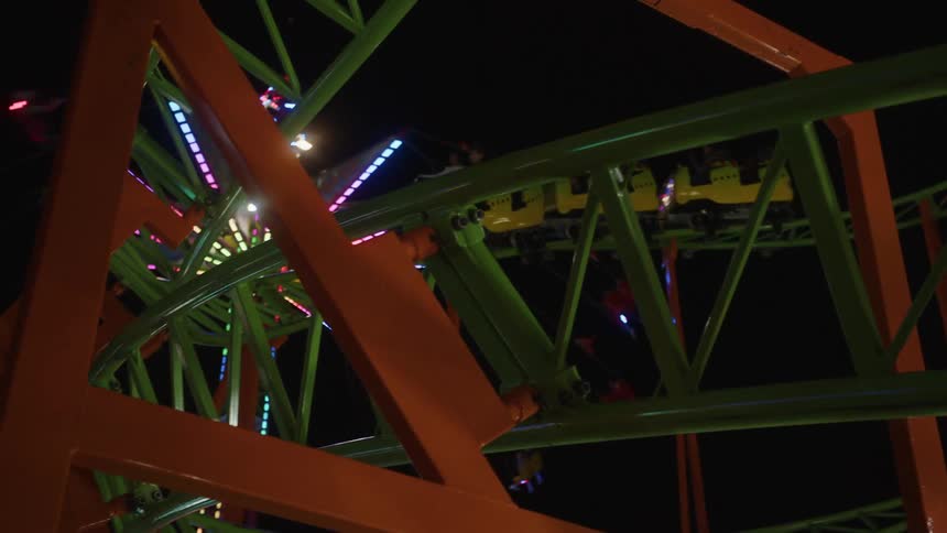 Roller coaster moving and operating in an amusement park at night