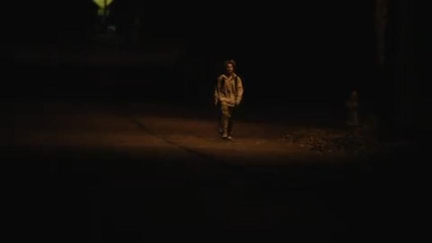 A child walks down the very dark street at night