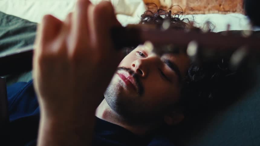 A man is laying down and playing the guitar