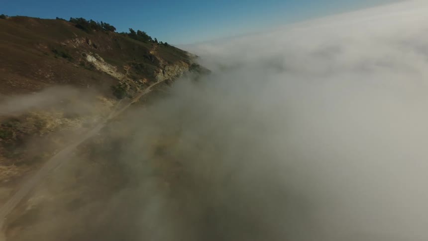 Aerial panorama of a seaside mountain surrounded by fog
