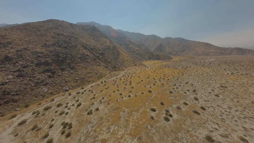 Aerial view of a highway with vehicle traffic amid mountains with sparse vegetation