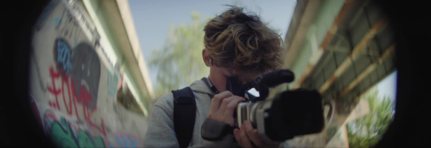 Boy using a professional filming camera outdoors