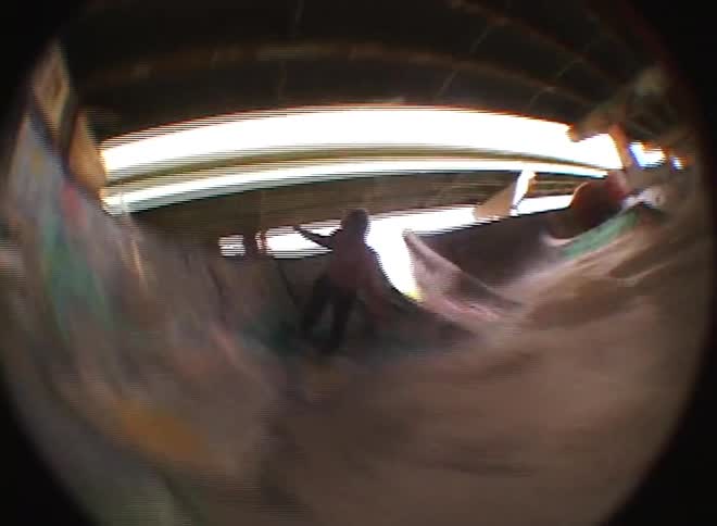 Young man performing skateboarding tricks on a track below an overpass