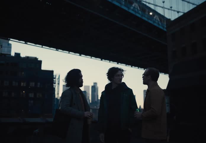 Three friends talk by the bridge in the city