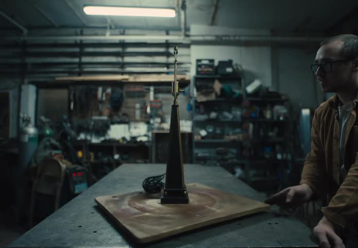 Man in a workshop examines a lamp base standing on a rotating wooden board