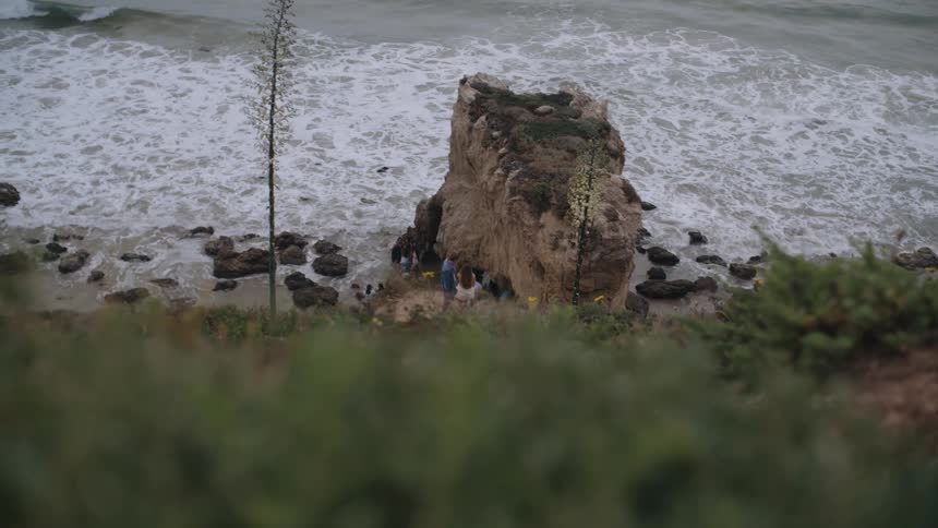 Small group of people on a rock by the sea