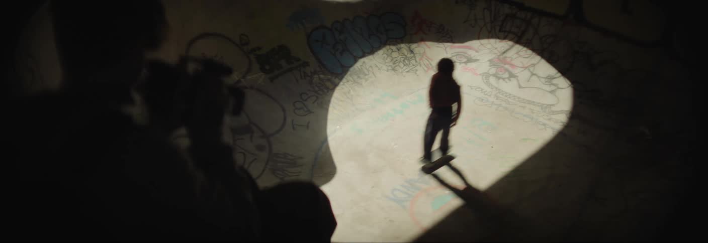 Person with a professional camera filming a teenager skateboarding on a rink