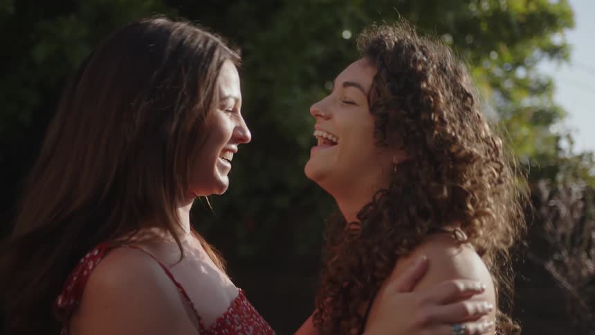 Two women hug each other and laugh
