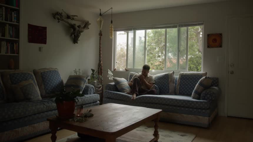 Man sitting on the couch in the living room giving his cat a kiss