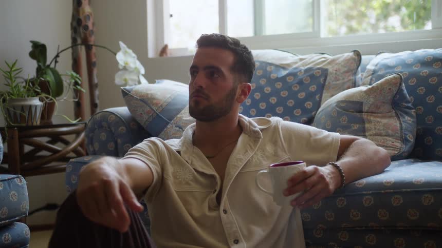 Man sitting on the floor of a living room holding a mug