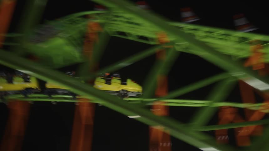 People having fun on a roller coaster at an amusement park at night
