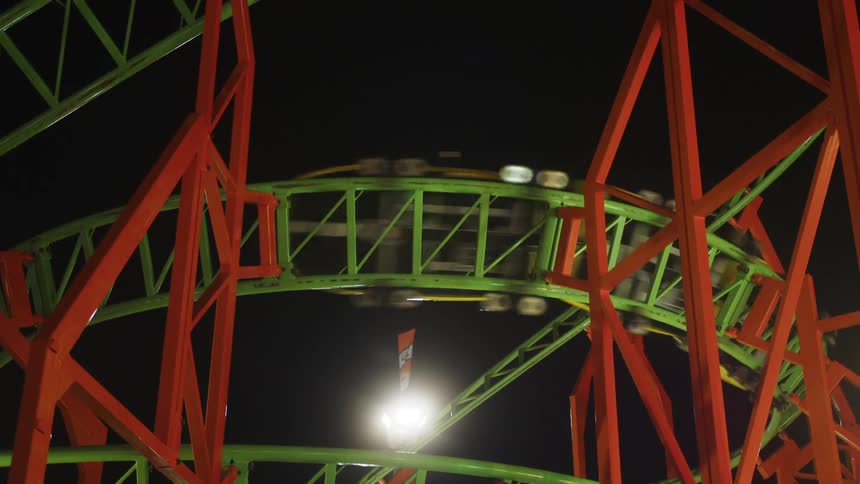 People having fun on a roller coaster ride at an amusement park at night