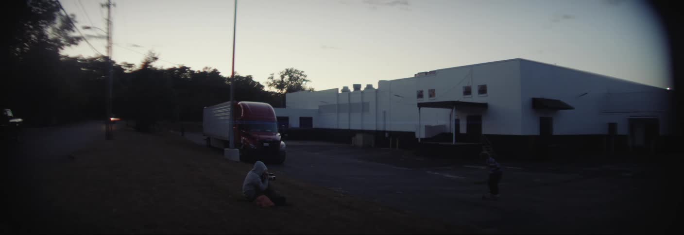 A teenager is skateboarding outside the warehouse