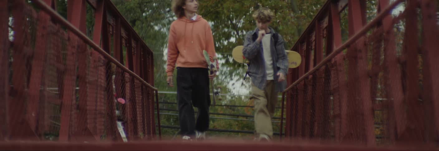 Two teenagers talk while crossing the bridge