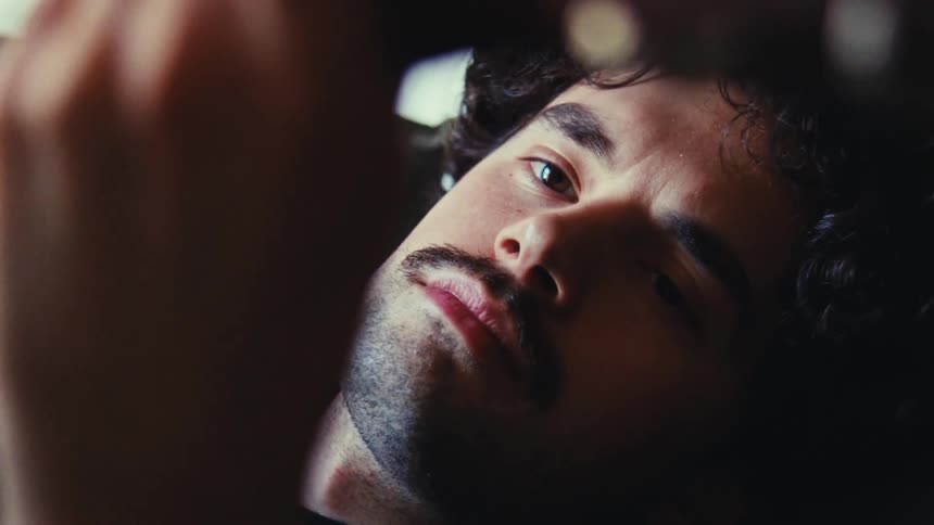 Close up of the face of a young man playing acoustic guitar