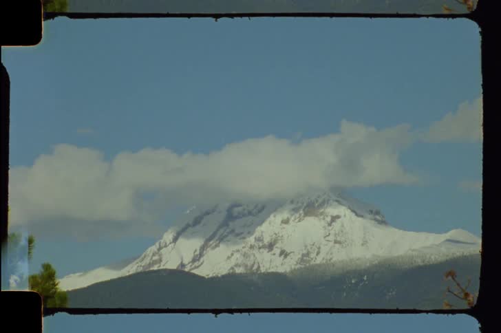 A snow capped mountain partially obscured by clouds