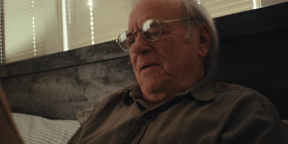 Elderly man lying in bed reading a book