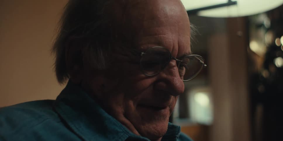 A man smiles while reading something
