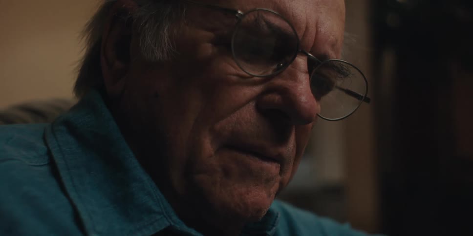 Elderly man sitting in living room and wearing glasses