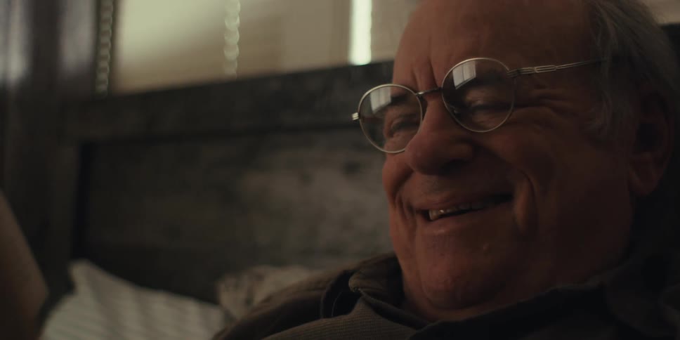 Elderly man smiles while reading a book in bed