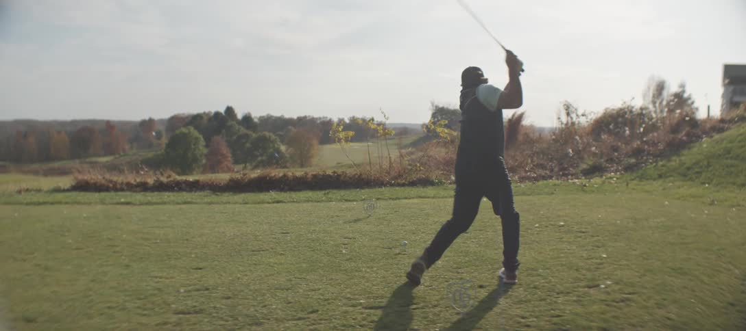 A man swings his club at the golf ball