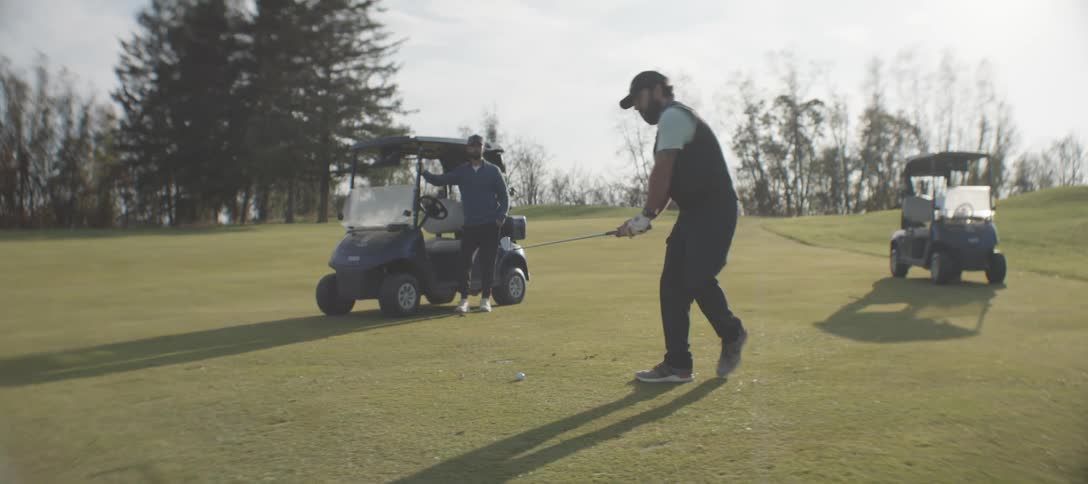 Male golfer getting ready to tee off as friend watches