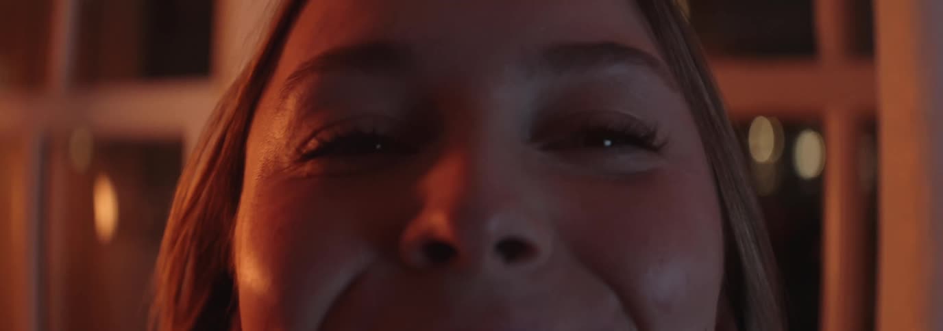Closeup of the upper part of the face of a smiling woman at night
