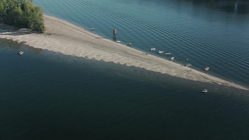 Aerial view of a lake with a thin strip of sand and trees