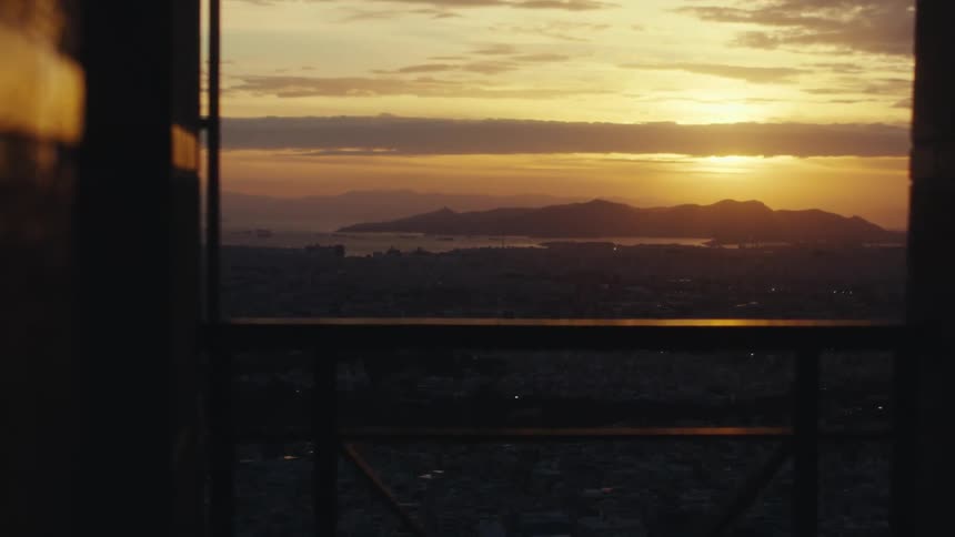 View from a balcony of an urban city with the sun rising on the horizon over the mountains