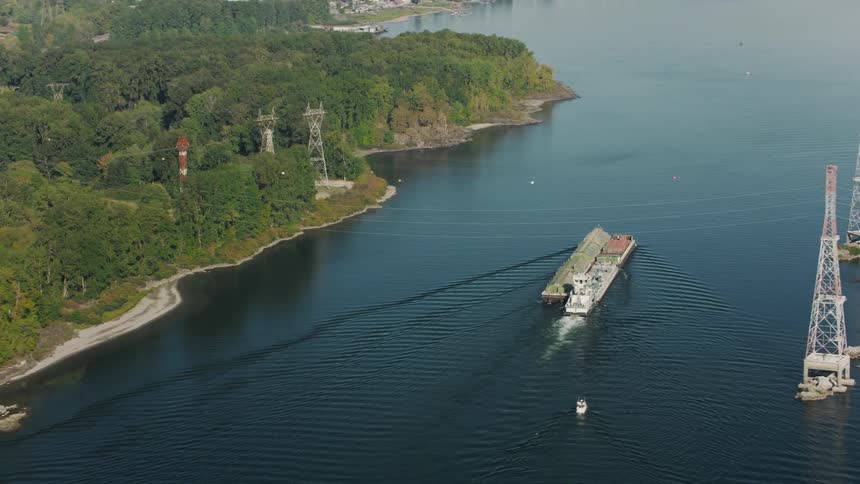 A tugboat pushes a barge across the water