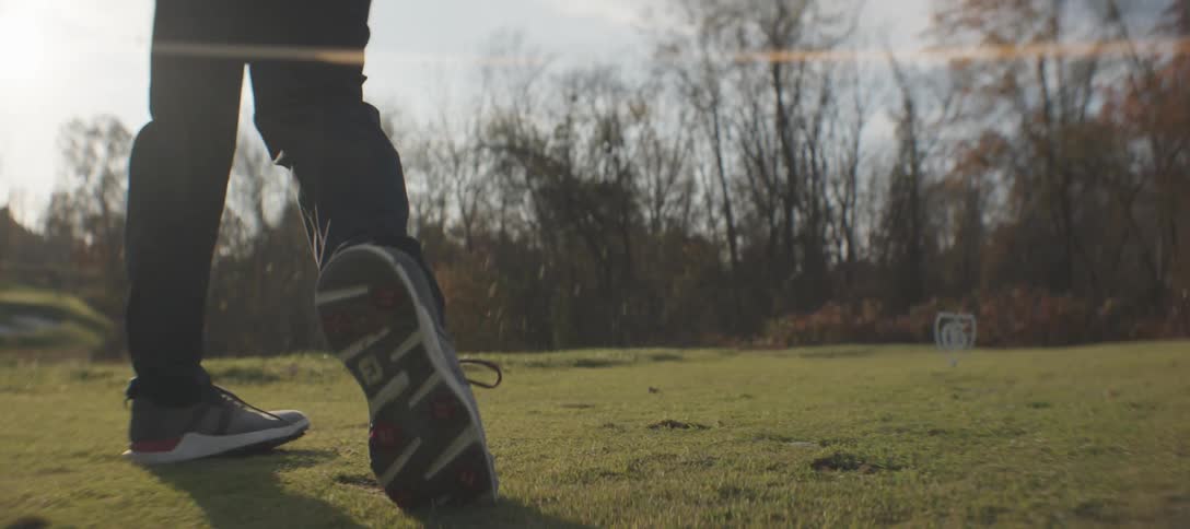 Legs of a person in motion while taking a golf swing on a course