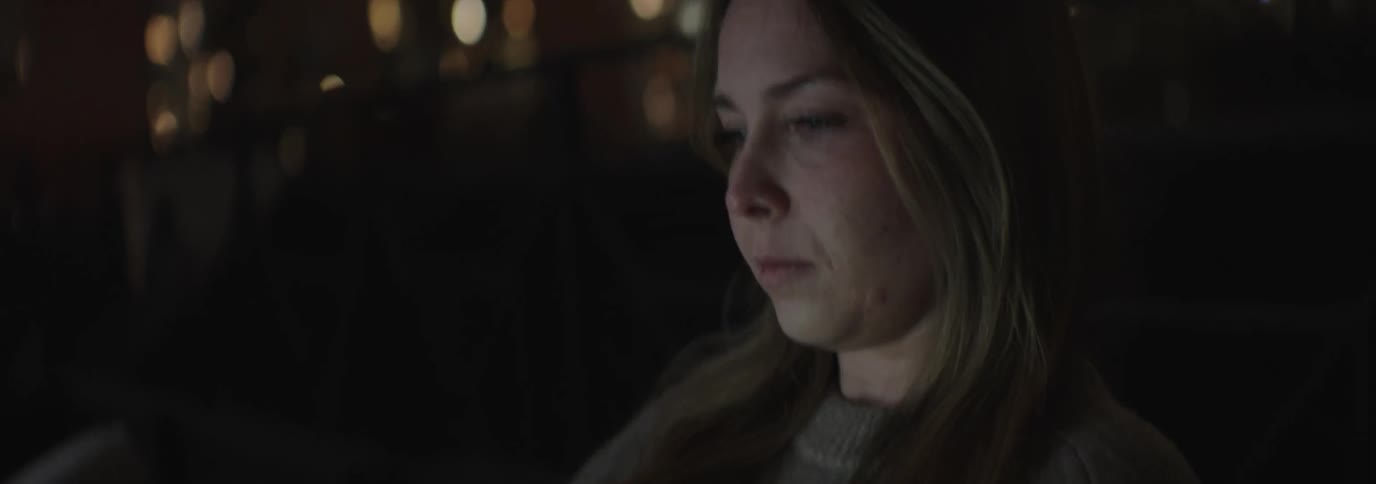 A woman is examining something in the dark