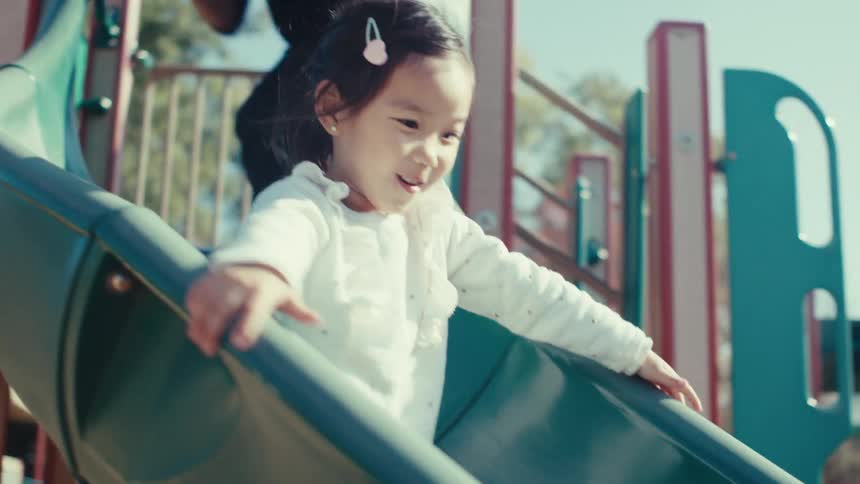 Father helping his daughter down a toy slide