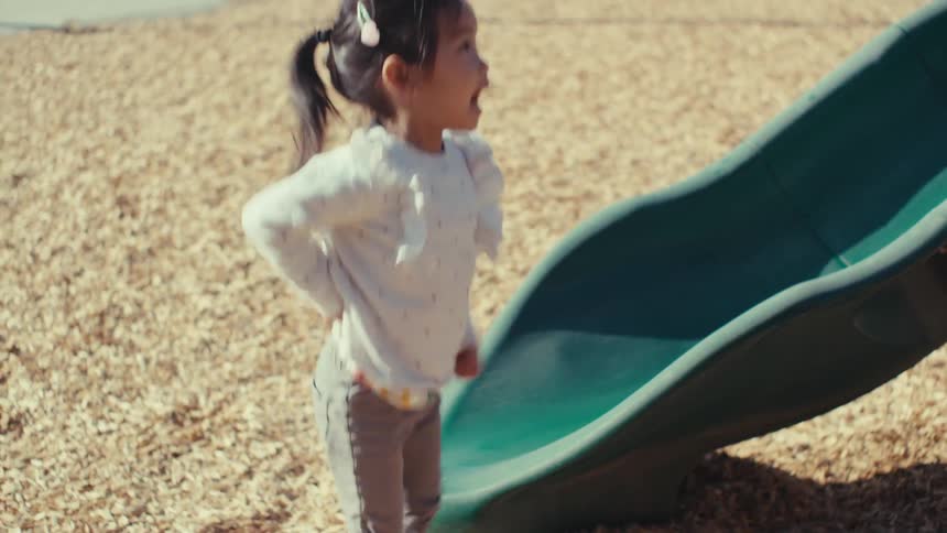 Father holding his daughter in his arms while they are at a playground