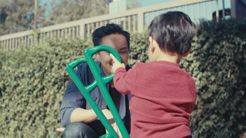 Little boy having fun playing with his father in an outdoor sand playground