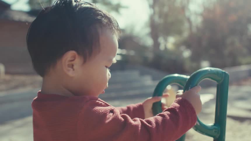 Toddler plays on the playground on a sunny autumn day