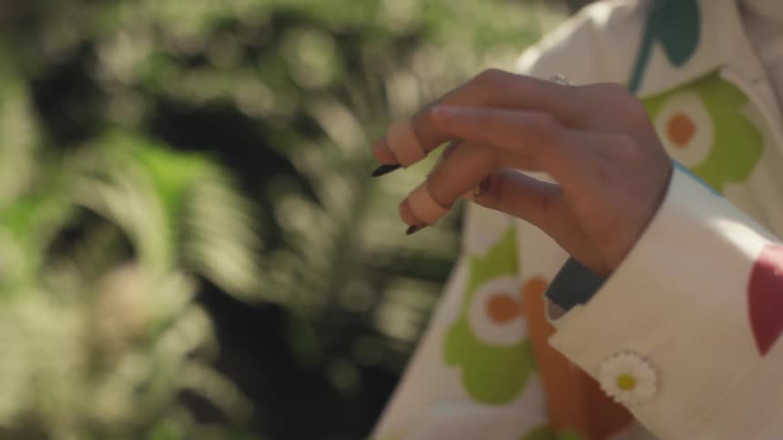 A womans hand has her fingers wrapped in bandages as she moves her arm to the right slowly