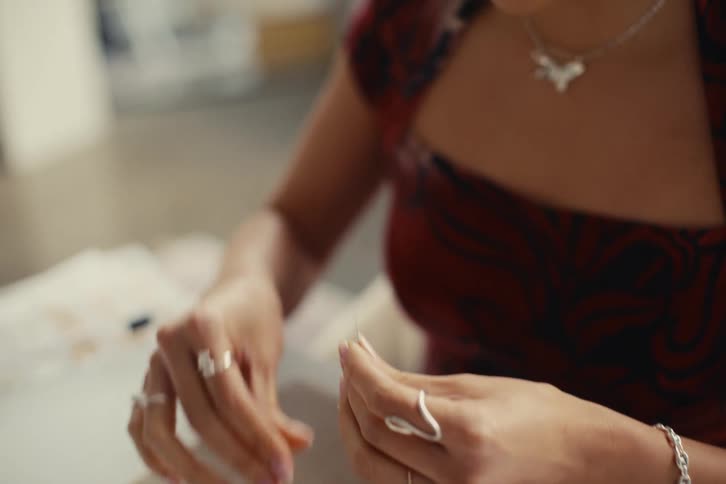 A jewelry designer sits at a table and makes a pearl necklace