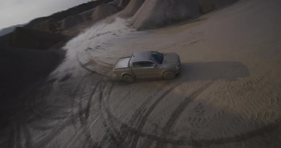 A pickup truck driving in a place full of mud on the ground and it is all dirty and skidding