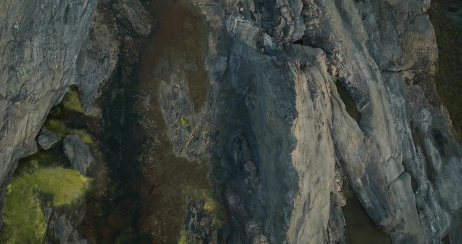 Boulders fill one of the crevices in pale mountainous terrain