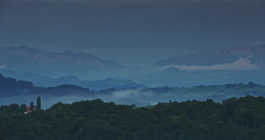 Horizon of layered mountains softly veiled by mist and trees