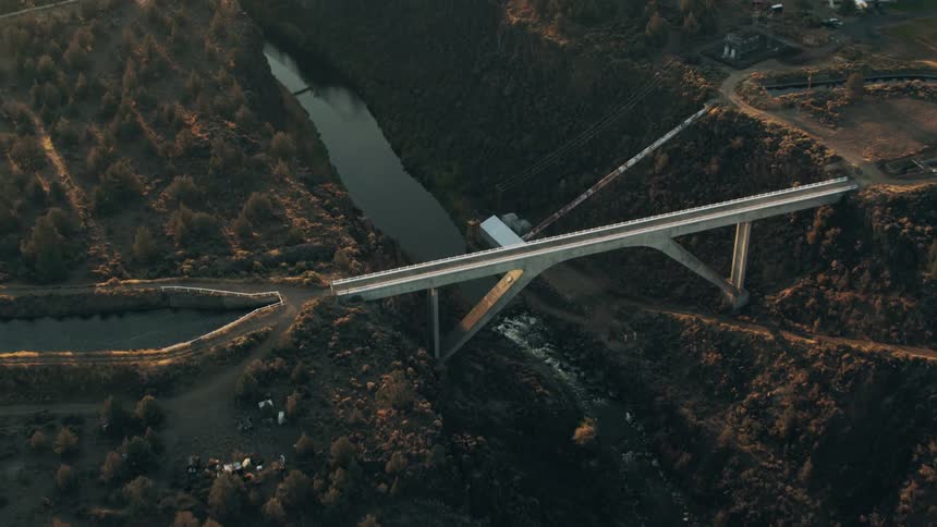 Concrete arch bridge over a ridge surrounded by vegetation during dusk or dawn