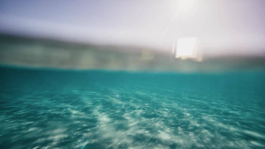 Underwater view of a crystal clear blue sea with the sun reflecting