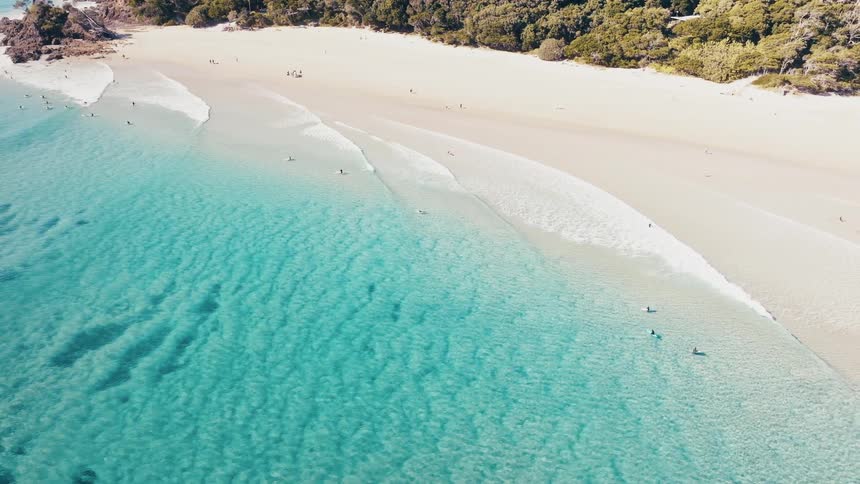 Aerial view of a beach with crystal clear waters and swimmers