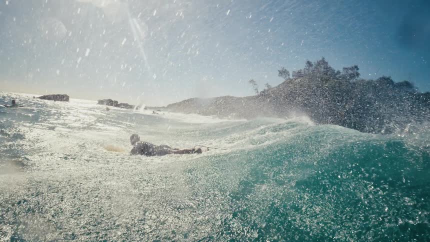 Two men are surfing in the rough water