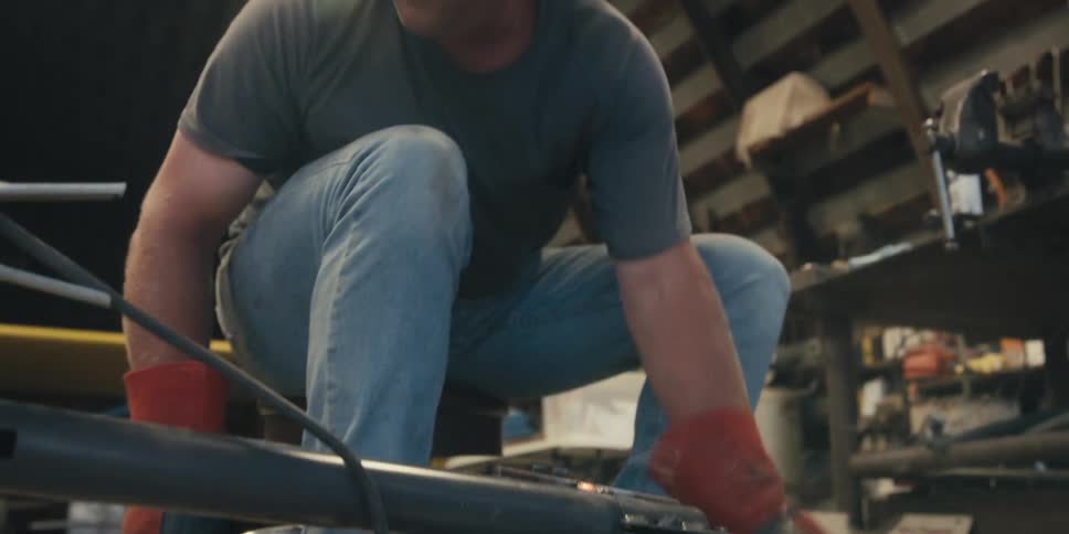 A person in protective gear is placing metal pieces together to weld them