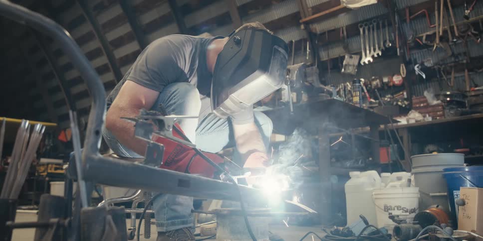 Man sitting welding a metal