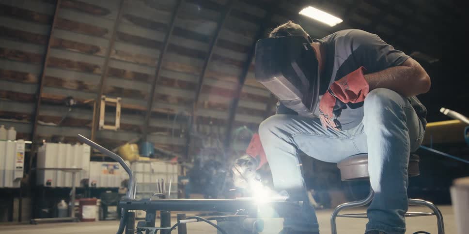 Man sitting in a workshop operating a welding tool
